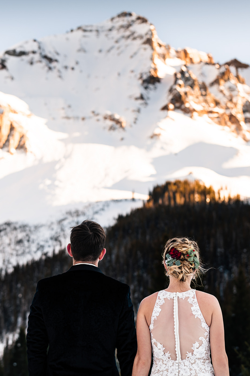 wedding couple looking at snow covered mountain peak, near Telluride, Colorado, ©The Outlovers