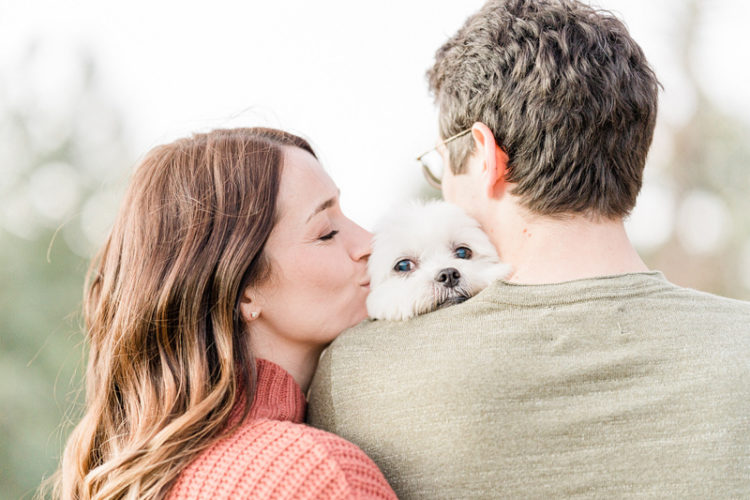 dog-friendly engagement session ideas, woman kissing dog that is snuggling against man's shoulder ©Mel Schroeder Photography